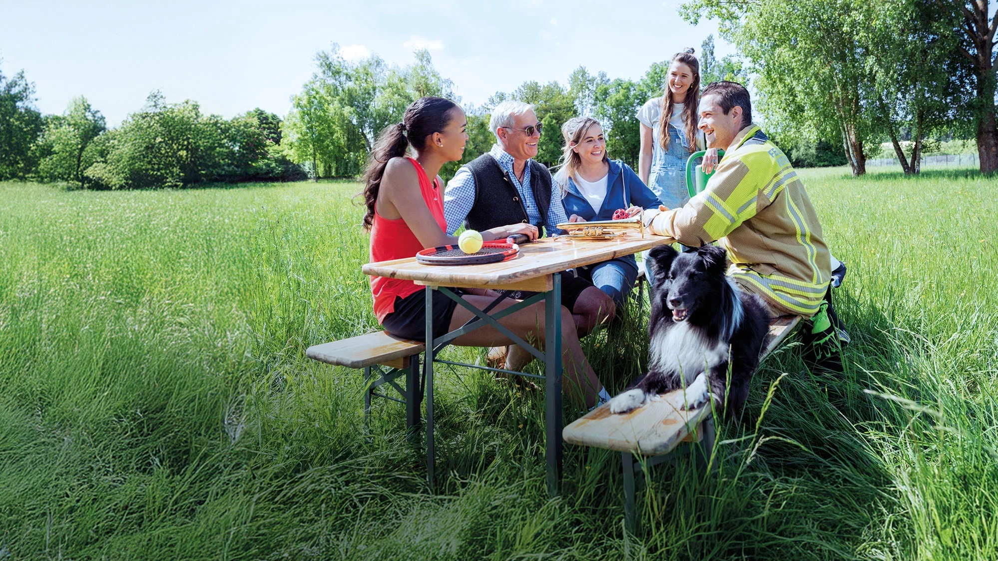 Eine Gruppe fröhlicher Vereinsmitglieder zusammen an einem Tisch im Freien